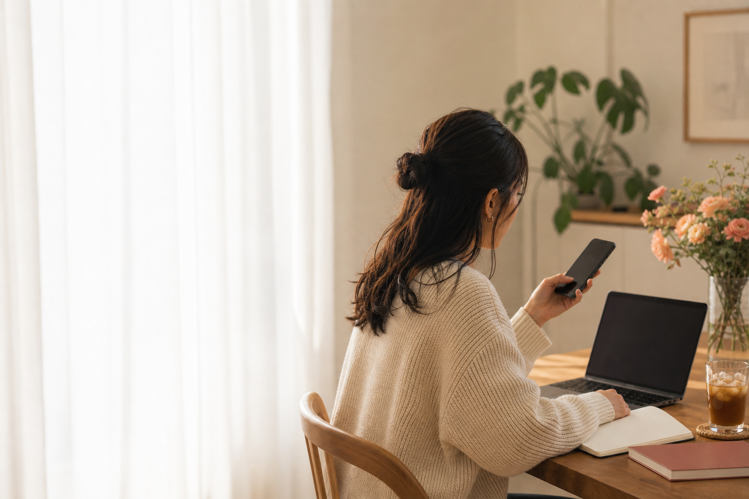 In a bright room, a person checks a phone while taking a break at a desk